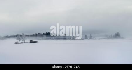 Panorama der schönen nebligen Winterlandschaft mit gefrorenen Bäumen und Holzhaus Stockfoto