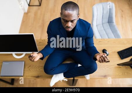 Afroamerikanische Männliche Meditation Im Büro In Der Nähe Von Computer Stockfoto