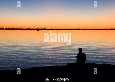 Ein Junge wird vor einem wunderschönen Sonnenuntergang über dem Lake Hefner in Oklahoma City geschilhoutet. Stockfoto