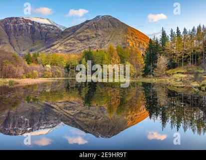 Glencoe, Schottland: Ein kleiner Teich mit Herbstspiegelungen und die Berge von Glen Coe bei Sonnenuntergang Stockfoto