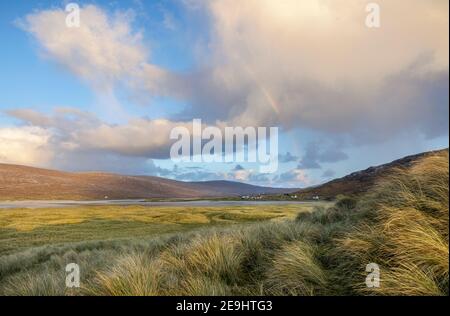 Isle of Lewis and Harris, Schottland: Regenbogenwolken und Regenbogen über den Dünengräsern in der Nähe von Luskentire Beach auf South Harris Island Stockfoto