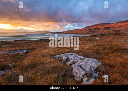 Isle of Lewis and Harris, Schottland: Felsbrocken im Machair mit der weiten Weite des Luskentire Strandes bei Sonnenuntergang auf der Isle of Harris Stockfoto