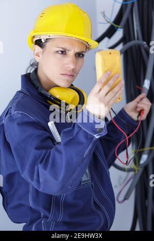 Elektrikerin verwendet ein digitales Messgerät, um die Spannung zu messen Stockfoto
