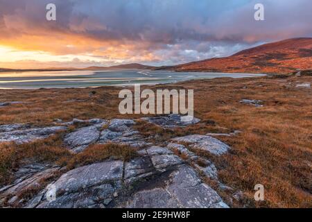 Isle of Lewis and Harris, Schottland: Felsbrocken im Machair mit der weiten Weite des Luskentire Strandes bei Sonnenuntergang auf der Isle of Harris Stockfoto