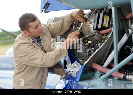 Mann, der mit einem Schraubenschlüssel an einem Flugzeug arbeitet Stockfoto