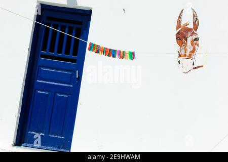 Santorini, Griechenland farbenfrohe Wäscheklammern hängen an der Wäscheleine vor dem traditionellen weiß getünchten Haus mit blauem Besatz. Stockfoto