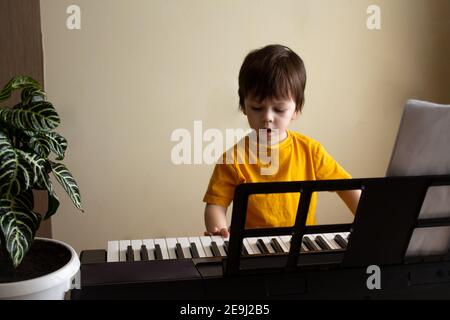 Ein Junge spielt den Synthesizer. Kleinkind lernen, Klavier zu spielen. Hände des Kindes auf der Tastatur. Frühe Entwicklung und Bildung Konzept Stockfoto