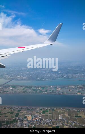 Japanischer Flugzeugflügel über Nagashima, Nagoya-Stadt in Japan. Luftaufnahme vom Beifahrersitz. Stockfoto