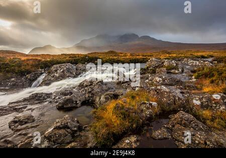 Isle of Skye, Schottland: Rauschende Gewässer des Flusses Sligachan und brechendes Licht auf die Black Cuillin Mountains in der Ferne. Stockfoto