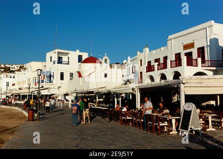 Mykonos, Griechenland Besucher flanieren neben den Restaurants und Cafés rund um den Hafen von Mykonos-Stadt. Stockfoto