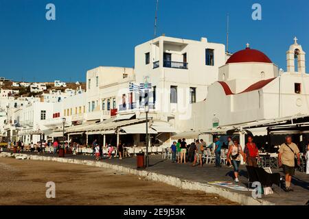 Mykonos, Griechenland Besucher flanieren neben den Restaurants und Cafés rund um den Hafen von Mykonos-Stadt. Stockfoto