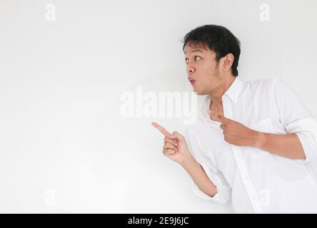 Junge asiatische Mann Krieg weißes Hemd ist überrascht und schreiend Wow mit dem rechten Zeigefinger auf grau isoliert Hintergrund Stockfoto