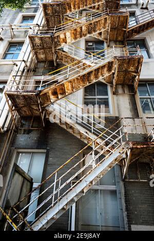Die Feuerflut des hohen Gebäudes, sehr alt und sehr verrostet auf der Rückseite des Gebäudes, verfallene und gefährliche Street Art Fotografie. Stockfoto
