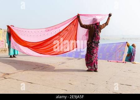 Nach dem Waschen im Ganges halten die Frauen ihre Saris in der Sonne, um sie zu trocknen. Stockfoto