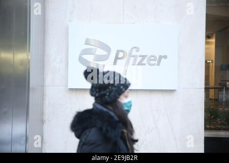 New York City, NY, USA Frau, die am Pfizer World Headquarters in der 42nd Street in Manhattan vorbeiläuft Stockfoto