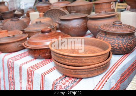 Traditionelle Keramikkrug auf dekorativischem Handtuch. Schaufenster der handgefertigten Ukraine Keramik in einem Straßenmarkt mit Keramik Töpfe und Tonteller outd Stockfoto