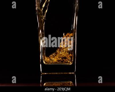 Nahaufnahme des Gießen von frischem Apfelsaft in das Glas. Schwarzer Hintergrund. Zeitlupe. Gesunde Lebensmittel, Vitamine, Früchte Stockfoto