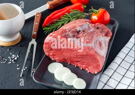 Frisches und rohes Rindfleisch. Ganzes Stück Filet für Steaks und Gewürze bereit, auf dunklem Hintergrund zu kochen. Stockfoto