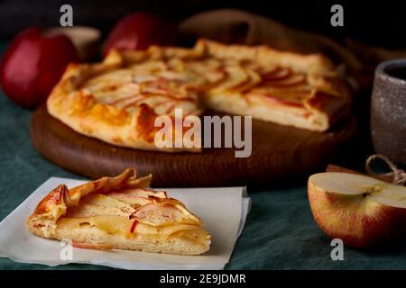 Apfelkuchen mit Stückchen Galette mit Früchten, süßes Gebäck in Scheiben auf dunkelgrüner Tischdecke Stockfoto
