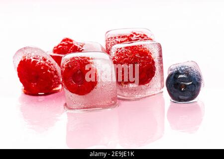 Himbeer-Eiswürfel auf rosa glänzenden Hintergrund Stockfoto