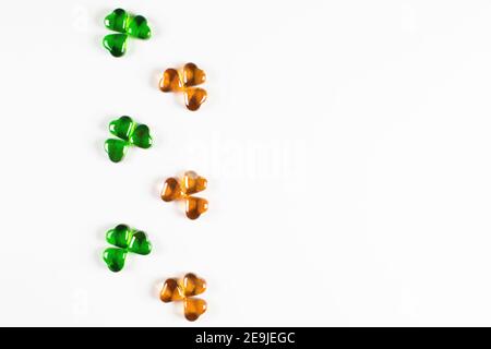 Shamrock Symbole aus grünem und orangefarbenem Glas Herzen auf Weißer Hintergrund Stockfoto