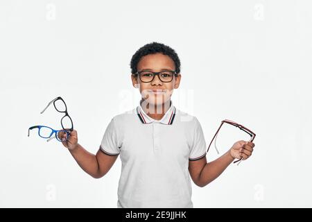 Afroamerikanischer Junge hält viele stilvolle Brillen in den Händen, für Sehkorrektur für Kinder. Isoliert auf Weiß Stockfoto