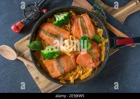 Eine Pfanne mit gebratenem Lachs und cremiger Pasta Stockfoto