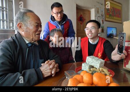 Peking, Chinas Provinz Jiangxi. Februar 2021, 3rd. Mitarbeiter der Gemeinde besuchen Dorfbewohner und helfen ihnen, mit ihrem Sohn, der in der Autonomen Region Guangxi Zhuang im Süden Chinas arbeitet, über Video-Link im Dorf Quantang der Gemeinde Shuibei in der Stadt Xinyu, Provinz Jiangxi im Osten Chinas, zu plaudern, 3. Februar 2021. Quelle: Peng Zhaozhi/Xinhua/Alamy Live News Stockfoto