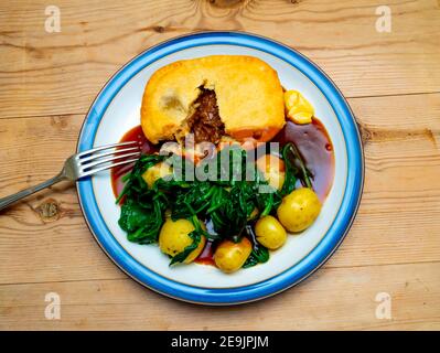 Mittagessen ein traditioneller Yorkshire Steak Pie mit neuen Kartoffeln serviert Spinat Senf und Soße Mittagessen ein traditionelles Yorkshire Steak Pie Serviert mit neuem Topf Stockfoto