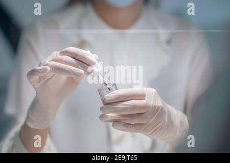 Nahaufnahme Bild von Nagelkünstler Hände in Handschuhe tun Nagellack Stockfoto