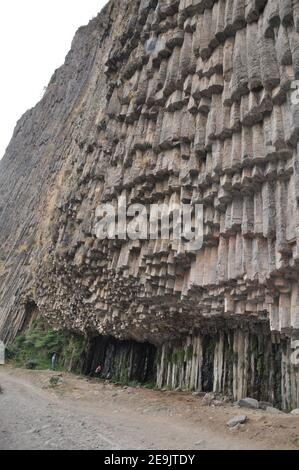 Faszinierende Ansicht des Mannes, der unter Basaltsäulen in der Garni-Schlucht, Armenien, steht Stockfoto