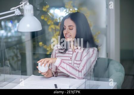 Dunkelhaarige Frau mit einem Glas Handcreme Stockfoto