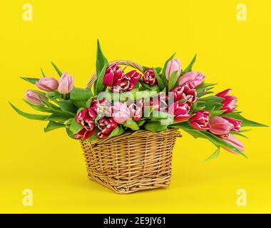Korb mit bunten Blumensträußen aus Tulpen auf Gelb Stockfoto