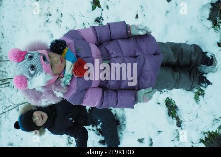 Kinder spielen Schneebälle im Winterwald. Stockfoto