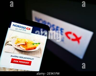 Smartphone mit Lachsgericht der deutschen Fast-Food-Restaurantkette Nordsee GmbH (Seafood) vor dem Firmenlogo. Fokus auf Telefonbildschirm. Stockfoto