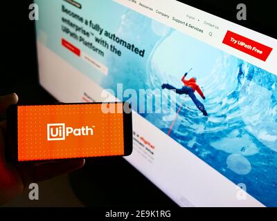 Person hält Handy mit Logo der Automatisierung Software-Entwicklung Unternehmen UiPath Inc. Auf dem Display vor der Webseite. Fokus auf Telefonbildschirm. Stockfoto