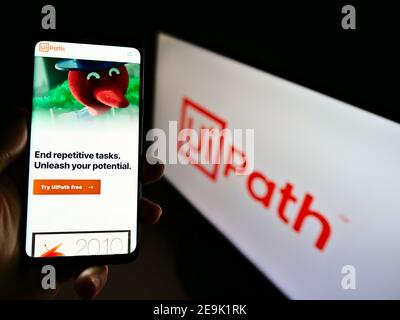 Person hält Handy mit Website der Software-Entwicklung Unternehmen UiPath Inc. Auf dem Display vor dem Logo. Konzentrieren Sie sich auf die Mitte des Telefonbildschirms. Stockfoto