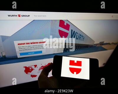 Person mit Mobiltelefon mit Logo des deutschen Konzerns Würth (Befestigungselemente, Schrauben) auf dem Display vor der Webseite. Fokus auf Telefonbildschirm. Stockfoto