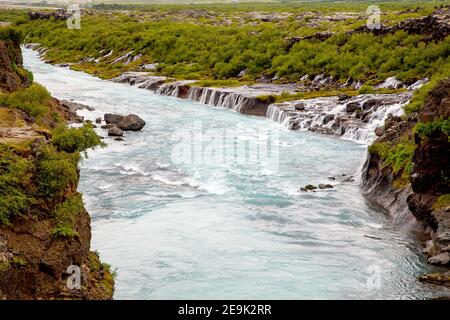 Hraunfossar mehr als Miniatur-Wasserfälle von Bächen über eine Entfernung von etwa 900 Metern aus dem Hallmundarhraun gebildet. Die Wasserfälle Stockfoto