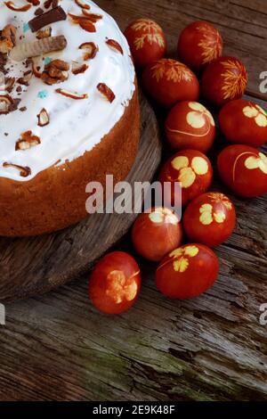 Osterkuchen und bunte Eier. Rustikales Essen auf einem Holztisch. Traditionelles Ei mit Zwiebelschale gefärbt. Muster aus Kleeblättern und Dillblättern. Klassisches Essen für Stockfoto