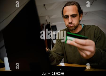 Kaukasisch gestresst Student kämpfen sitzen am Schreibtisch Online-Shopping mit Notebook Stockfoto