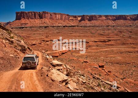 Geländewagen auf der White Rim Road, in Murphy Hogback, Murphy Point Cliffs in der Ferne, Canyonlands National Park, Utah, USA Stockfoto