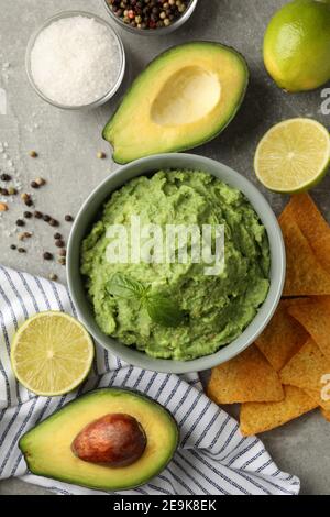 Konzept des leckeren Essens mit Guacamole und Zutaten auf grau Hintergrund Stockfoto