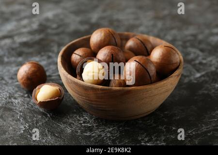 Schüssel mit leckeren Macadamia-Nüssen auf schwarzem rauchigen Hintergrund Stockfoto