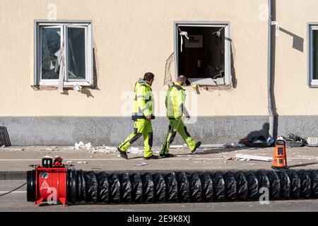 Memmingen, Deutschland. Februar 2021, 05th. Zwei Mitarbeiter des Stadtwerks Memmingen gehen an einer bayerischen Ambulanzstation des Roten Kreuzes vorbei, wo die durch eine Explosion ausgeblasenen Fenster zu sehen sind. Bei einer Gasexplosion im Gebäude wurden heute früh mehrere Personen verletzt. Quelle: Matthias Balk/dpa/Alamy Live News Stockfoto