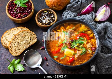 Hausgemachtes Fleisch Tomatensuppe mit Rindfleisch und Bohneneintopf, Gemüse auf einer Steinplatte. Stockfoto