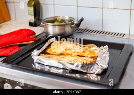 Kochen zu Hause Abendessen, im Ofen gebackenen Fisch mit Gemüse ist auf dem Herd Stockfoto