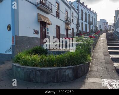 Firgas, Gran Canaria, Kanarische Inseln, Spanien 13. Dezember 2020: Blick auf die Straße Paseo de Gran Canaria mit Wasserfall Brunnen, Blumen und Keramik Stockfoto