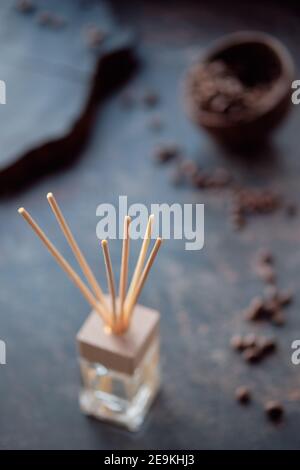 Lufterfrischer mit Bambusstäbchen und Parfüm aus Glas. Dunkle strukturierte Hintergrund.belebende Kaffee Geruch. Veralterter dunkler Hintergrund. Geröstete Kaffeebohnen Stockfoto