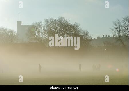 Eton, Windsor, Berkshire, Großbritannien. 5th. Februar 2021. Silhouetten im frühen Morgennebel in Eton mit Blick auf Windsor Castle. Sonnenschein ist für heute prognostiziert mit Regen und möglicherweise Schnee für das Wochenende. Quelle: Maureen McLean/Alamy Live News Stockfoto